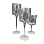 Trio de castiçais com velas criando iluminação acolhedora e efeitos de luz com arabescos.