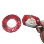 Conjunto de xícara e pires natalinos em cerâmica com acabamento delicado e detalhes inspirados em tricô para decoração de Natal.