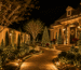 Área externa residencial completamente decorada para o Natal, com árvores iluminadas, arbustos, cascatas de LED no muro, caminho luminoso e detalhes natalinos, composição sofisticada