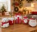 Composição de peças natalinas de cerâmica esmaltada em tons de branco, vermelho e dourado, incluindo Papai Noel, pequenas casas e árvores sobre um aparador elegante.