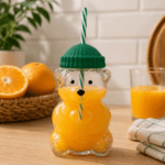 Garrafa de vidro com formato de ursinho, design delicado e tampa verde, perfeita para bebidas e para presentear.