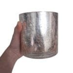 Peça de vidro rose gold com efeito craquelado, utilizada como vaso decorativo para flores e folhagens, mostrando sua versatilidade.