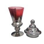 Vaso de vidro vermelho com detalhes prateados e tampa, destacando seu formato alto, elegante e imponente.