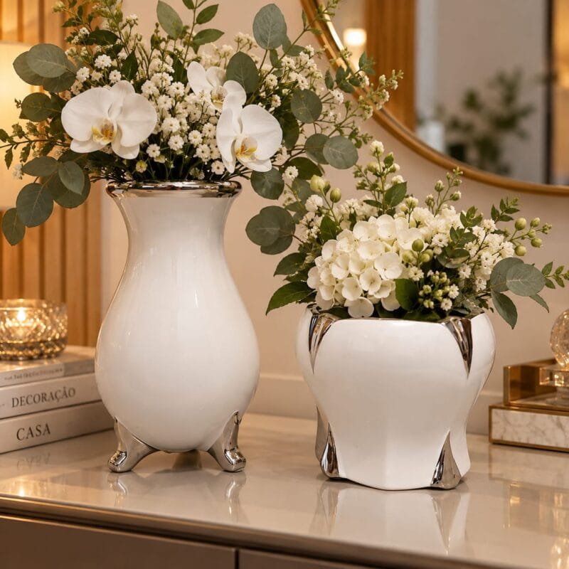 Conjunto com dois vasos decorativos de cerâmica branca e detalhes prateados, apresentado lado a lado para destacar os diferentes formatos e tamanhos.