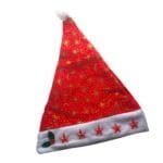 Vista completa do gorro natalino vermelho, destacando o formato triangular, o pompom branco, as estampas douradas e as estrelas de LED.