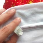 Gorro natalino vermelho confeccionado em tecido aveludado, com estampas douradas, pompom branco e estrelas de LED na faixa inferior.
